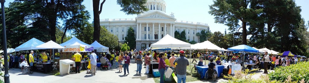picture of the capitol with a dozen resource booths with tents and lots of people milling around them