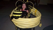 picture of a litle firl in a bee costume and her wheelchair is a honeycomb