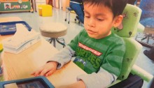 Picture of a little boy sitting at a desk using a communicaiton tablet