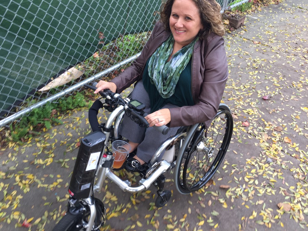 women smiling using her manual wheelchair with the firefly attachment 