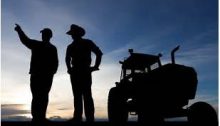 the silhouettes of two farmers standing next to a tractor