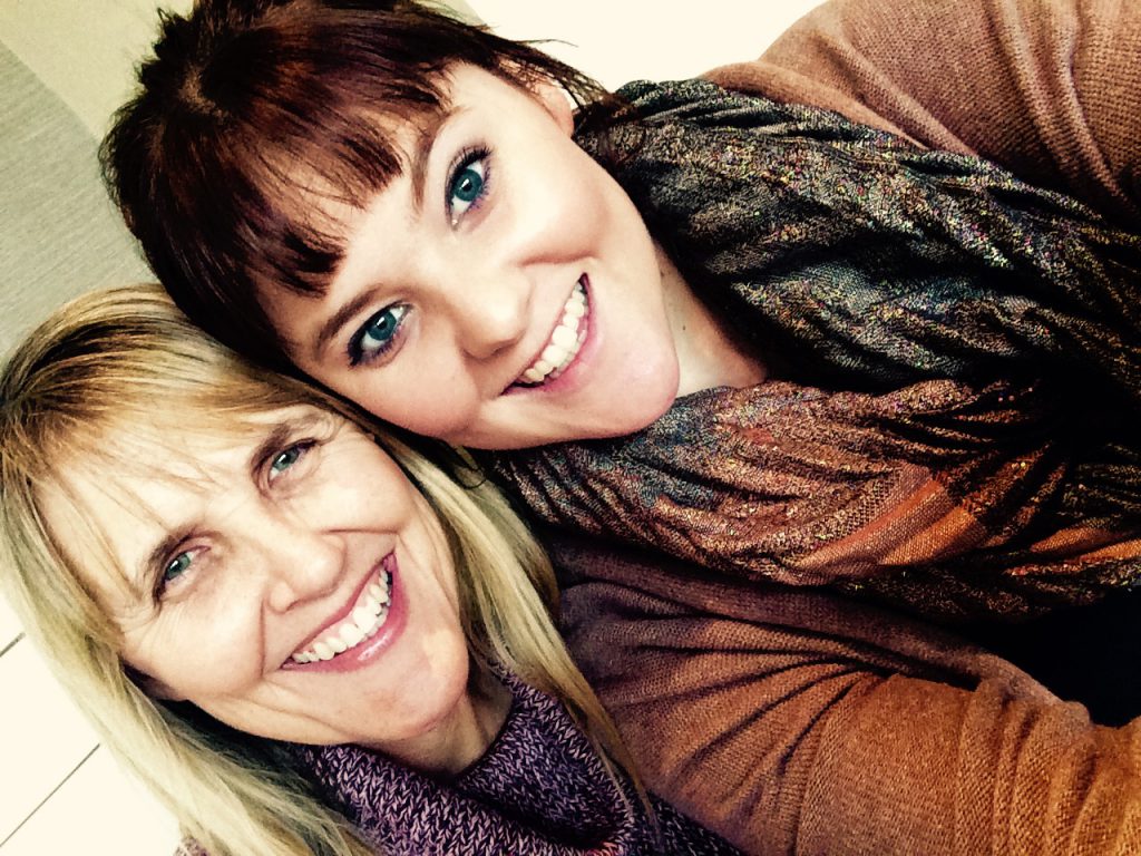 A mother and her adult daughter are smiling at the camera in a selfie.