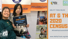 A woman in a power wheelchair smiling with an adolescent child by her side. The child is holding a sign that reads, "My 2020 Census participation matters!"