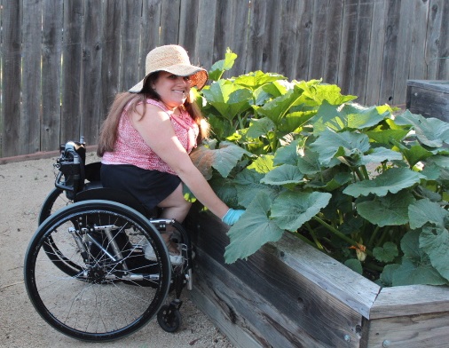 Woman in a wheelchair smiling with her above-ground planter boxes.