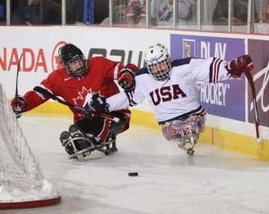 USA sled hockey team player and a Canadian sled hockey player both go after the puck on the ice rink. 