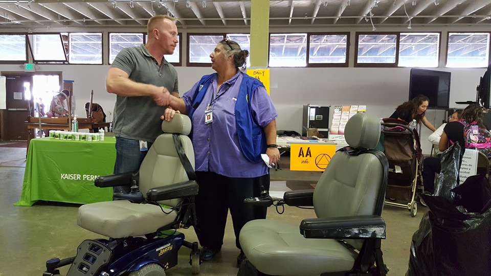 Clint Vigen from the CA Dept. of Rehabilitation and Teresa Favuzzi, Exective Director of CFILC shake hands over the power chairs they helped to get to the victims of the fire
