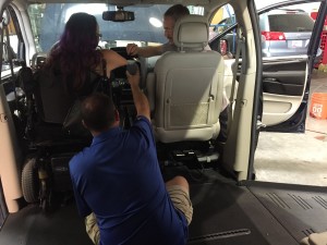 a man making adjustments in car while Josette is in driver's seat