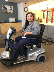 Photo of Ms. Gomez sitting and smiling in her new scooter 