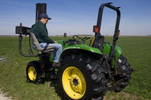 Man using a motorized transfer/lift chair to lift him into the tractor seat