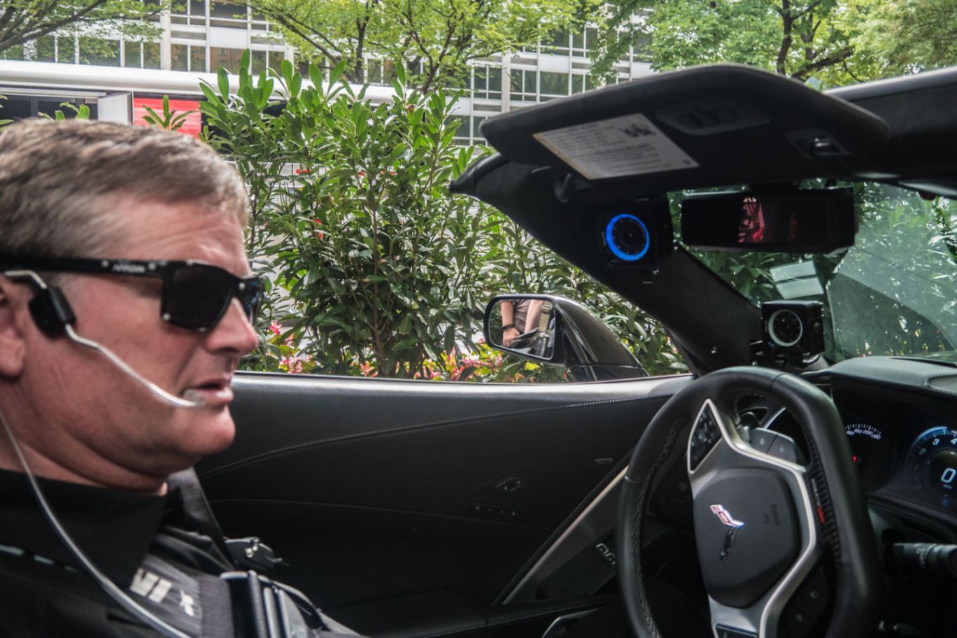Sam Schmidt sits in driver seat of his convertible corvette wearing specialized sunglasses and a headset that control his vehicle