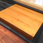 built- in light wood colored cutting board sliding out of the kitchen counter 