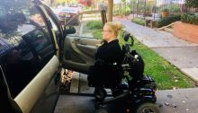 A woman is riding her power wheelchair up the ramp of her accessible van.