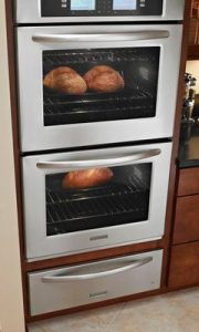 There are two stacked wall ovens with bread baking inside. 