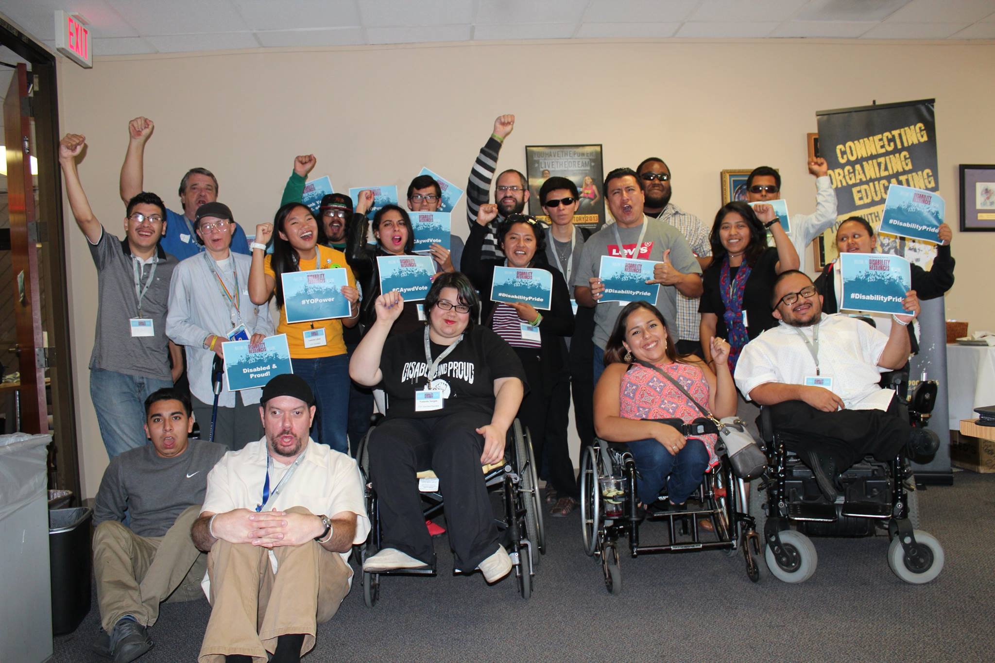 A group of people with disabilities are together with their hands up in a fist. 