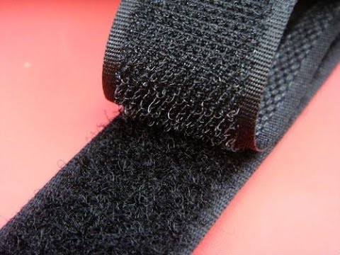 There is a red background. A black roll of velcro partially unrolled lays on top. 