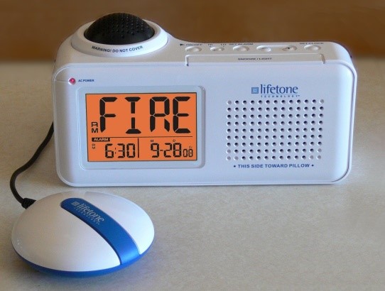 A fire alarm with a large display and speaker. There is a button attached that will vibrate with an alarm. 