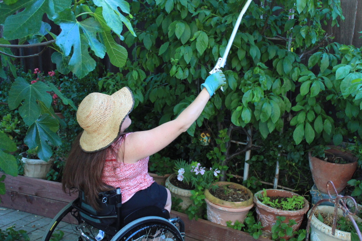 woman in wheelchair with floppy hat using a grab tool.