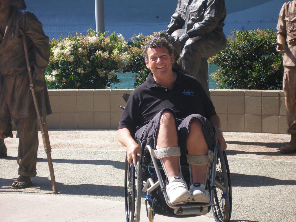 Photo of Angela Madsen in her wheelchair at a disabled veteran monument.