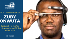 Black man with a visor device wearing a blue collared shirt and v-neck knitted sweater. Text: Spotlight on innovator Zuby Onwuta: Turning Personal Problem into Global Solutions. Where It's AT logo. #BHM2020