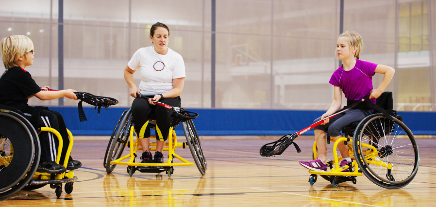 A trio of wheelchair users play wheelchair lacrosse.